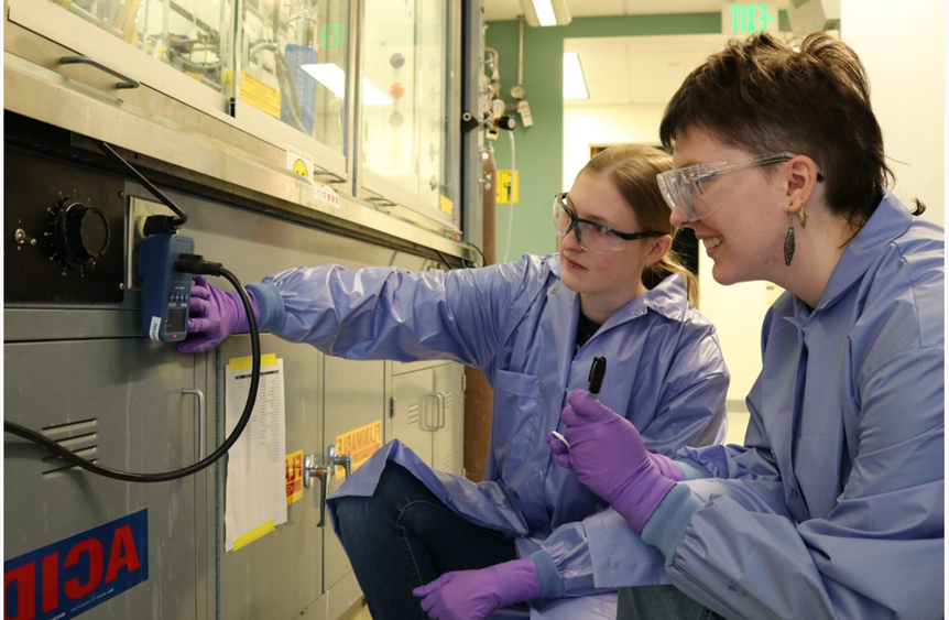 Two students in lab coats and goggles